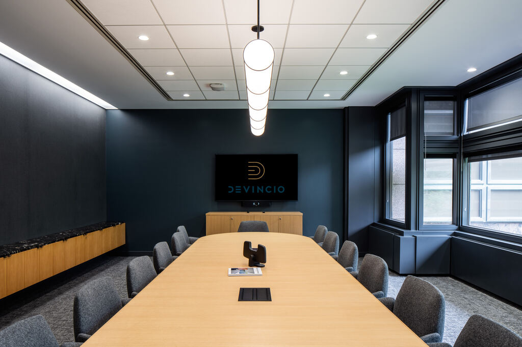 Conference room with dark walls, a long wood table, and wall display