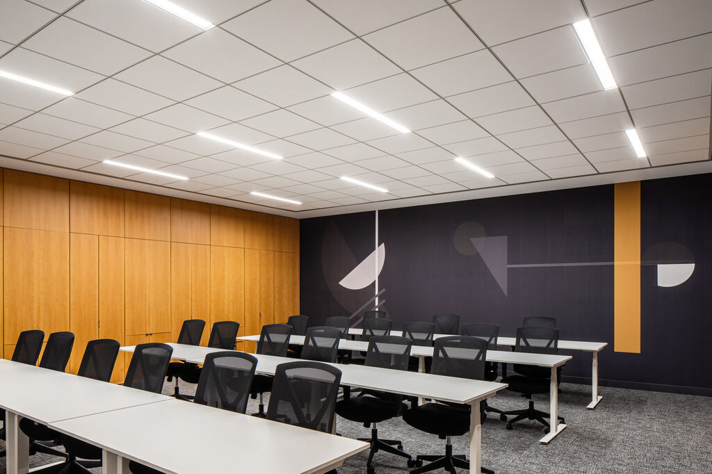 Larger meeting room with multiple tables, wall displays, and acoustic panels