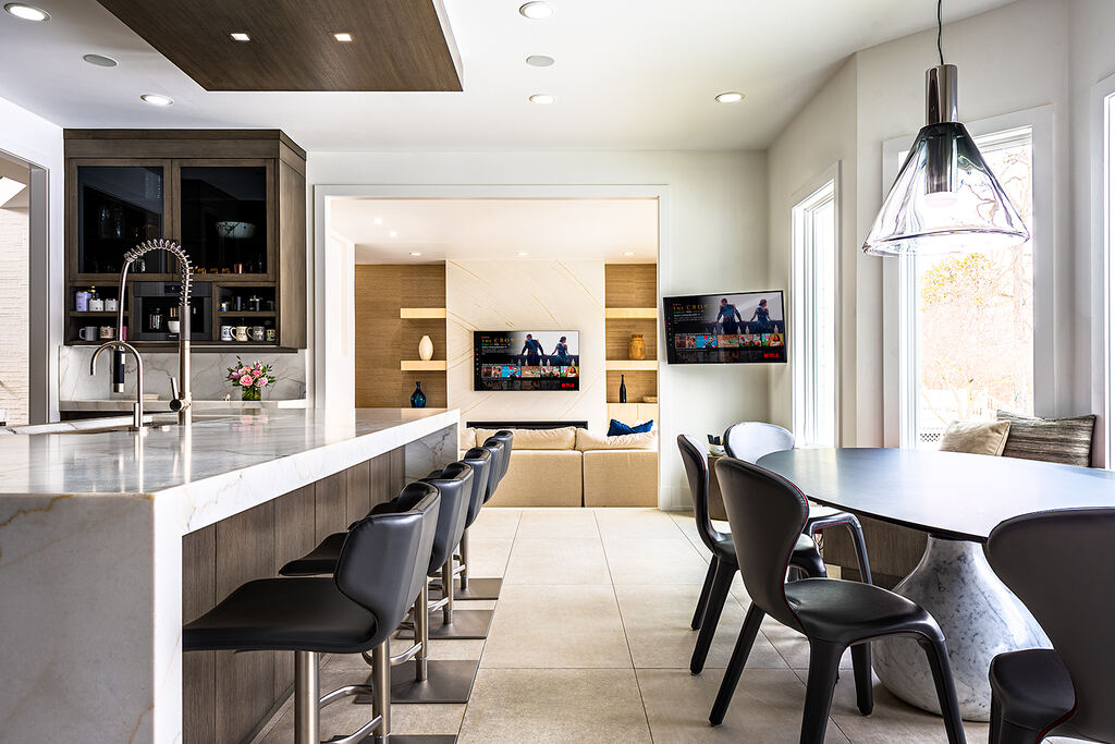 Kitchen with a marble island, dining table, and two wall-mounted displays in the adjoining living area