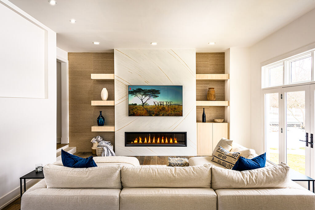 Living room with a wall-mounted display over a linear fireplace, built-in shelving, and sofa seating